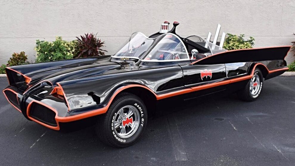 A black and red classic car sits parked outside.